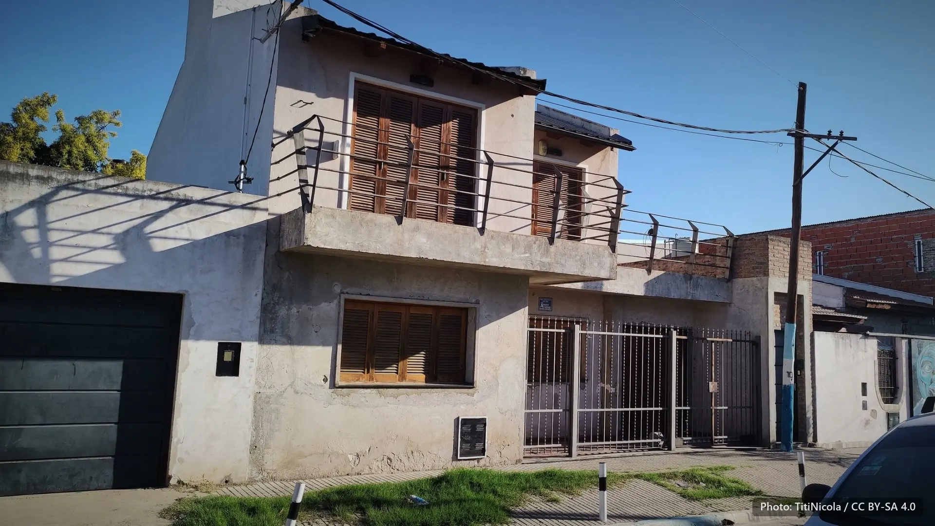 A house with shutters and an iron balcony under a hard blue sky, in the Rosario neighbourhood where Messi grew up.