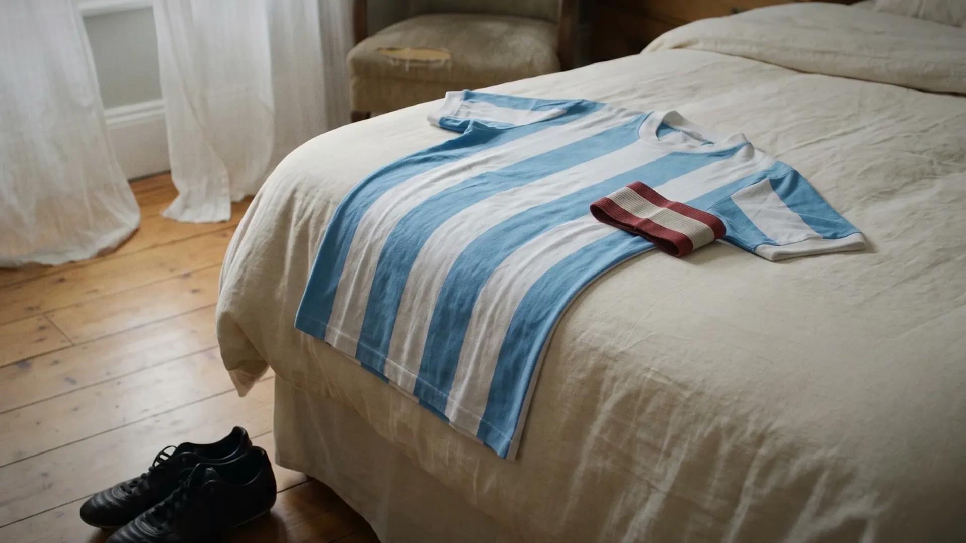 A striped shirt and a folded armband on a bed.