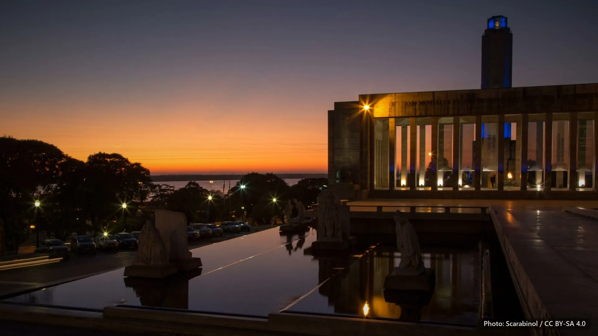The Monumento a la Bandera, Rosario, at dawn, with its reflecting pool and an orange sky.